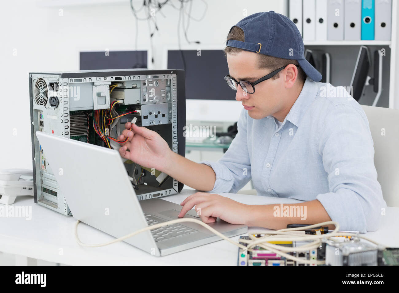 Ingegnere Informatico lavorando sulla console rotto con il computer portatile Foto Stock