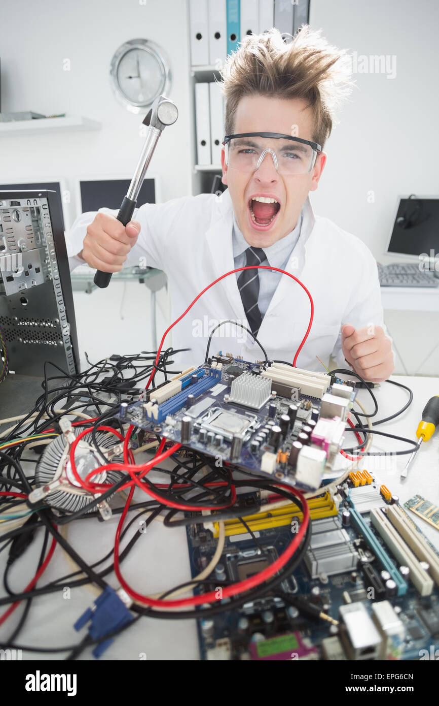 Arrabbiato ingegnere informatico azienda martello sulla console Foto Stock