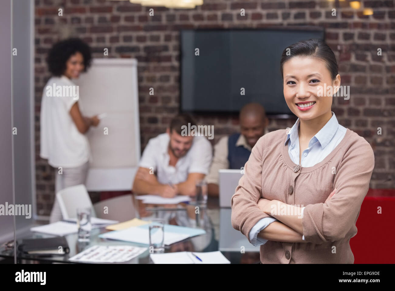 Sorridente giovane imprenditrice con colleghi in background Foto Stock