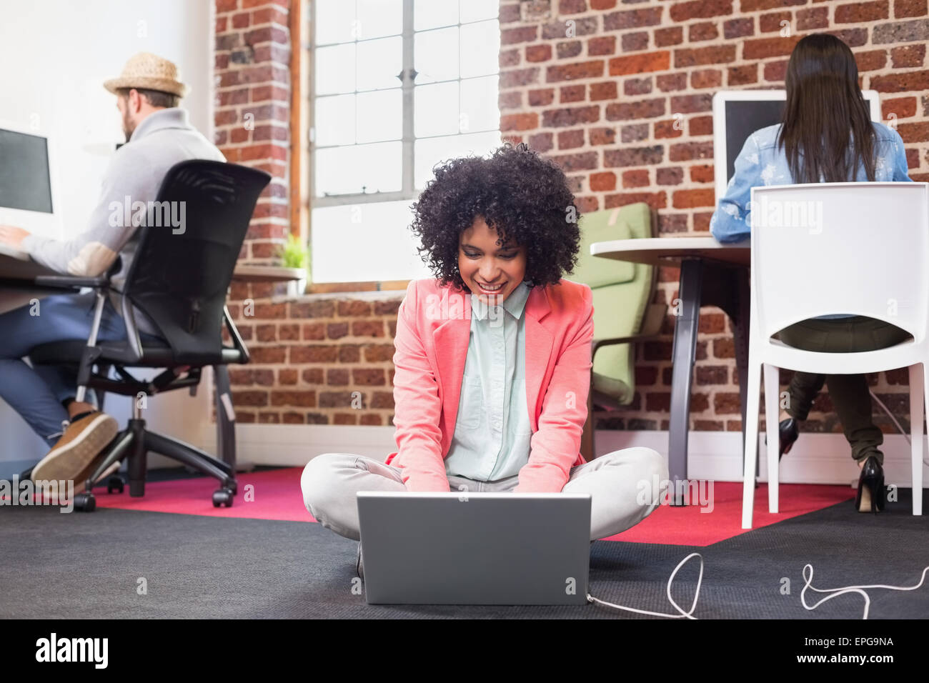 Donna con notebook con i colleghi dietro in ufficio Foto Stock