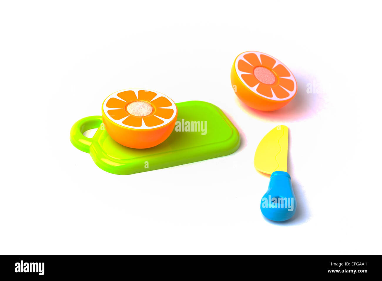 Un giocattolo di plastica arancione mikan su un tagliere essendo tagliato a metà con un coltello di plastica. Foto Stock