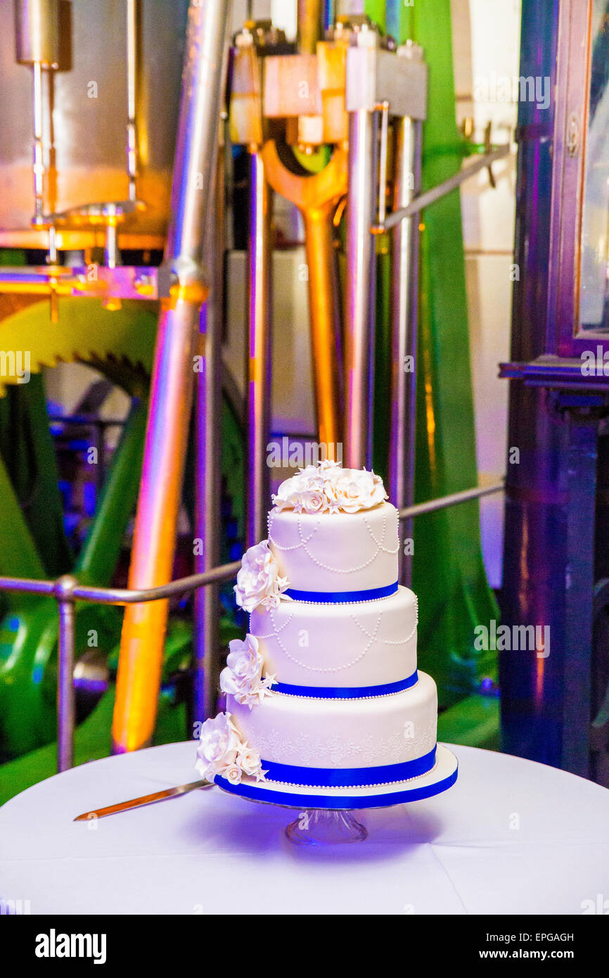 Torta di Nozze con fiori e nastro blu in un ambiente industriale Foto Stock