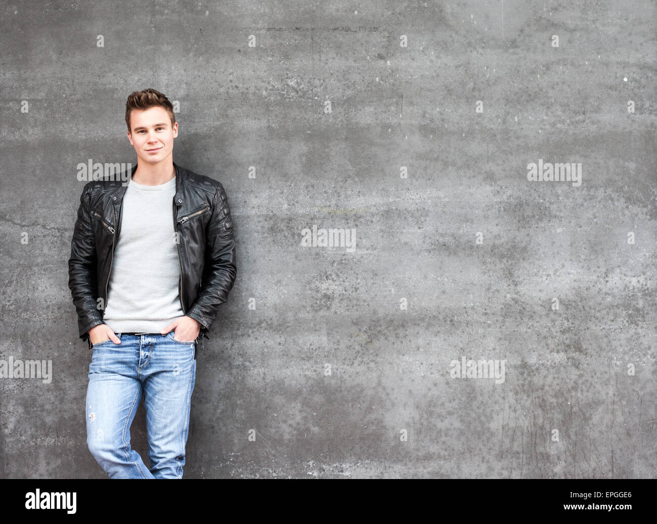 Casual giovane ragazzo in piedi di fronte a un muro di cemento Foto Stock