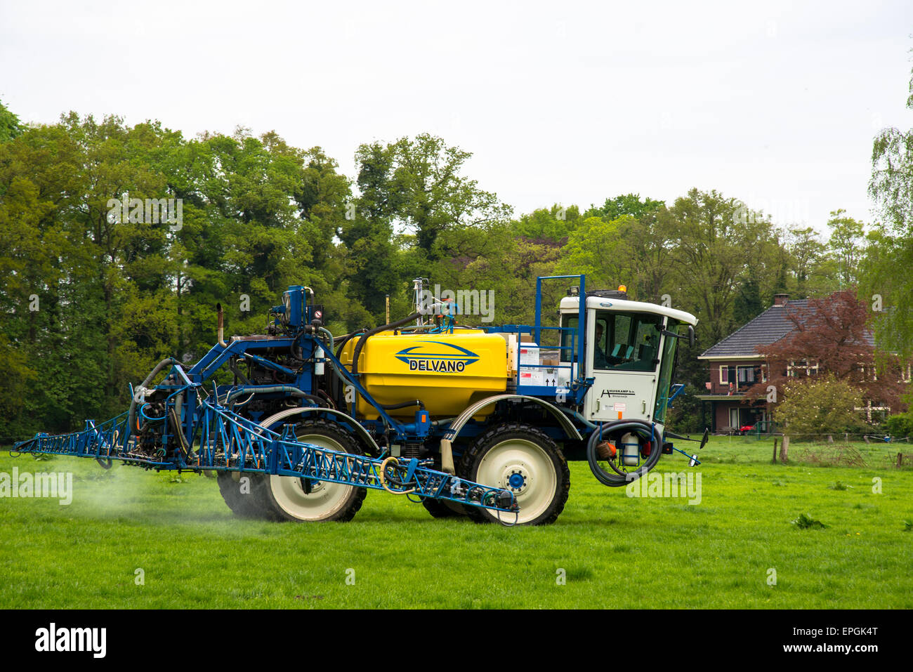 Contadino con il trattore spruzza il fertilizzante con il suo campo Foto Stock