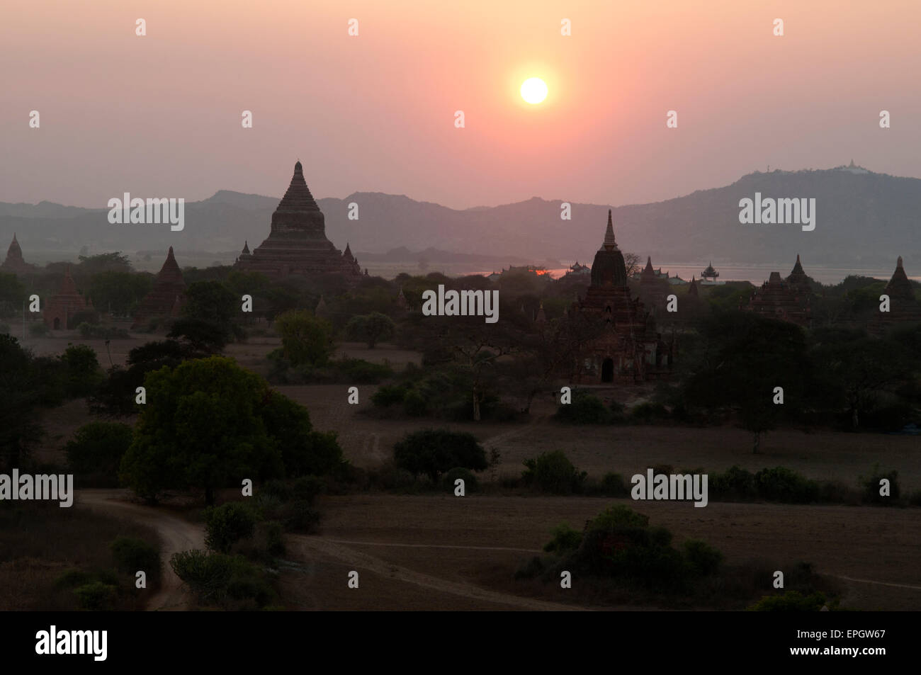 Le sagome scure dei templi di pietra contro il giallo bagliore del sole al tramonto a Bagan Myanmar Foto Stock