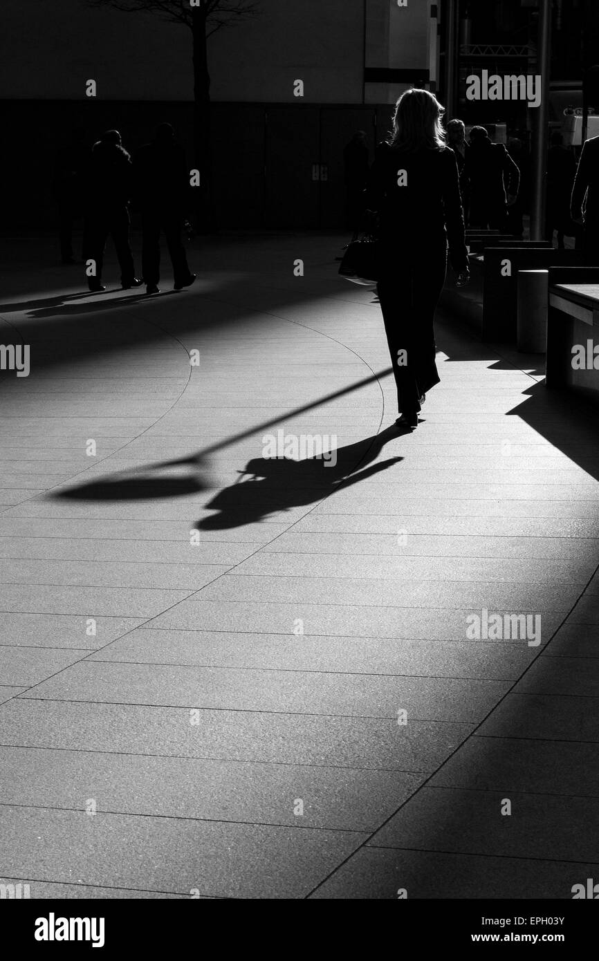 Una donna cammina passato " il Gherkin' nella luce Foto Stock