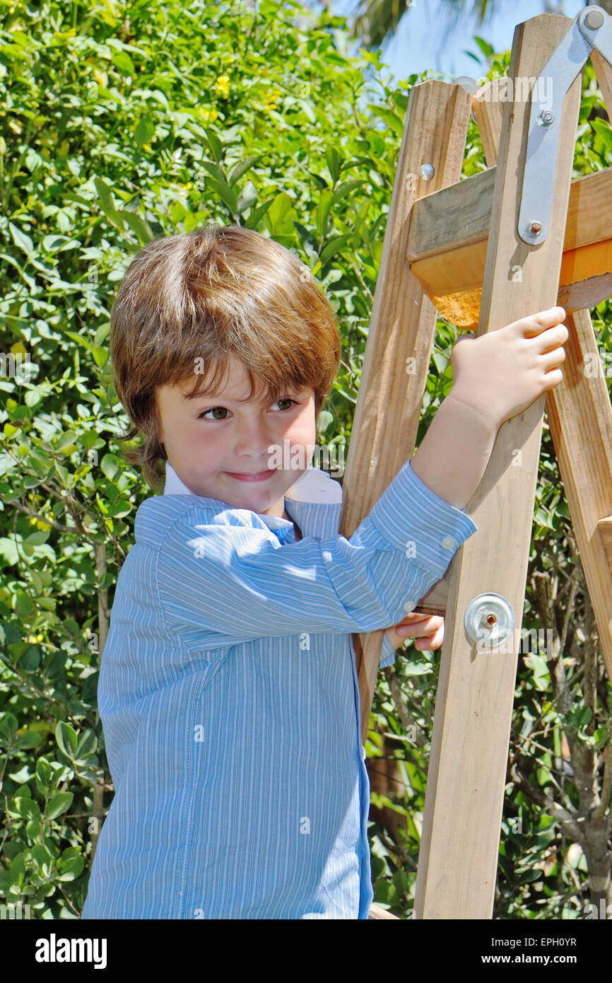 Il ragazzo con un sorriso pone sul passo scaletta Foto Stock