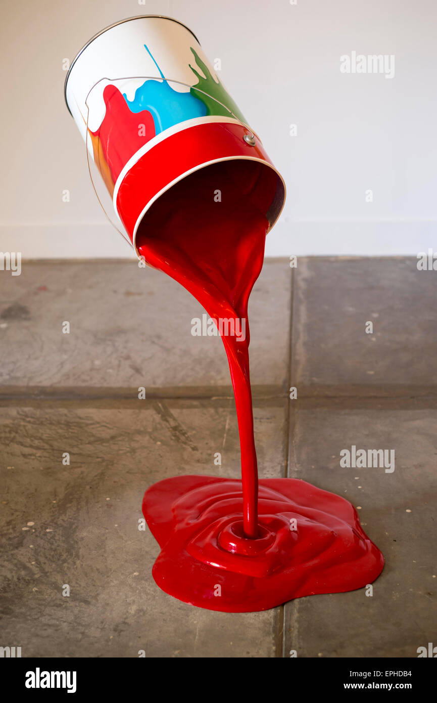 Barattolo di vernice rossa versando sul pavimento Foto Stock