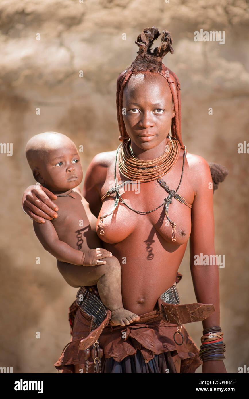 Africa, Namibia. Tribù Himba Village. Donna indigena tenendo il bambino. Foto Stock