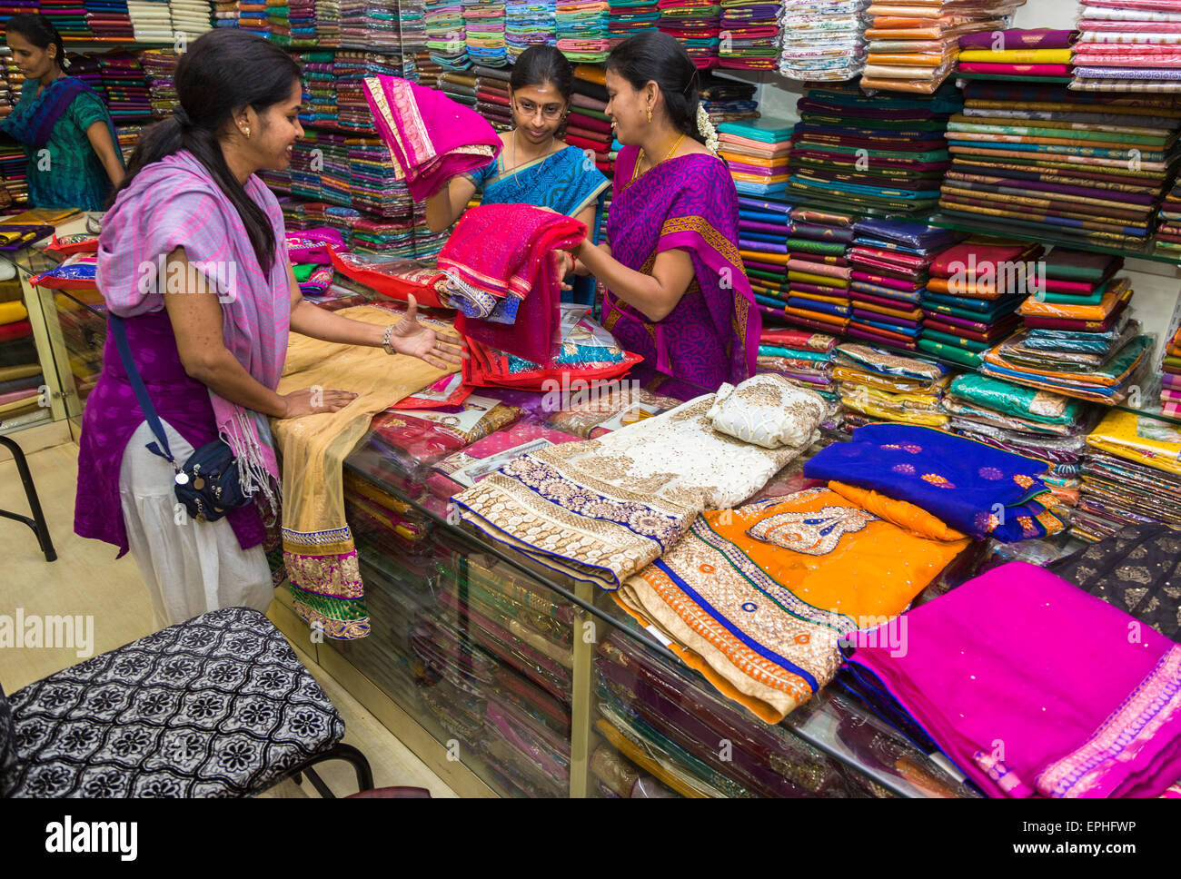 Donna locale che sceglie in un negozio di vestiti e tessuti con materiali dai colori vivaci per saris e costumi locali, Chennai, Tamil Nadu, India meridionale Foto Stock