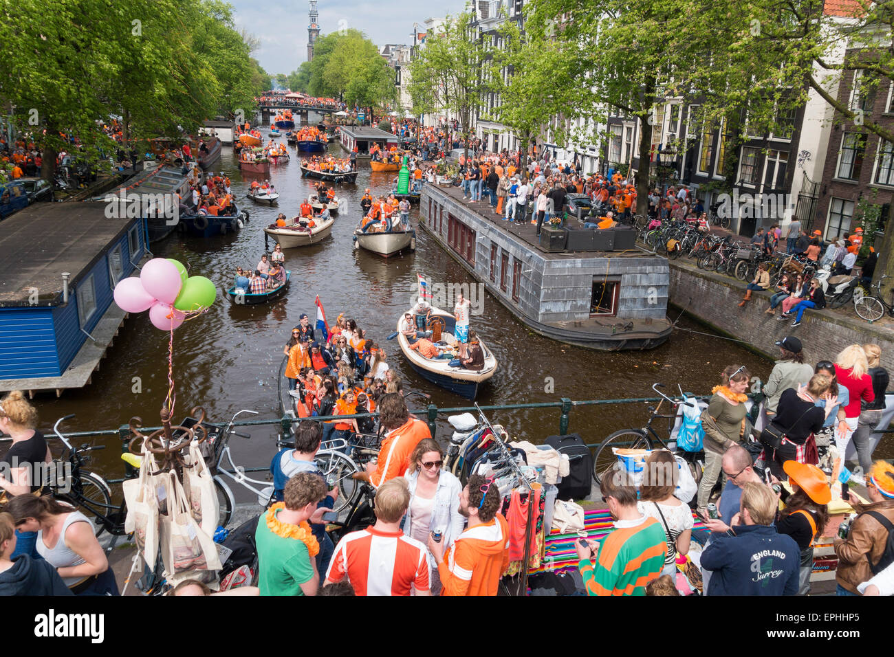 La folla celebra Koningsdag, Kings Day Festival in Amsterdam w barche sul canale Prinsengracht e Vrijmarkt sul ponte. Foto Stock
