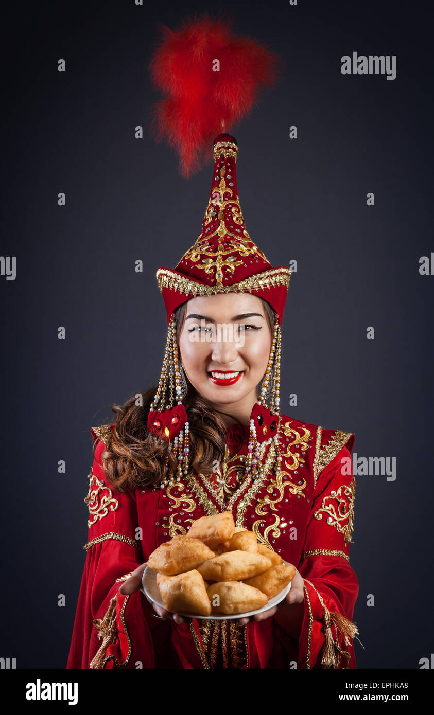 Woman in Red nazionale costume kazako tenendo la piastra con baursak pane alla celebrazione Nauryz Foto Stock