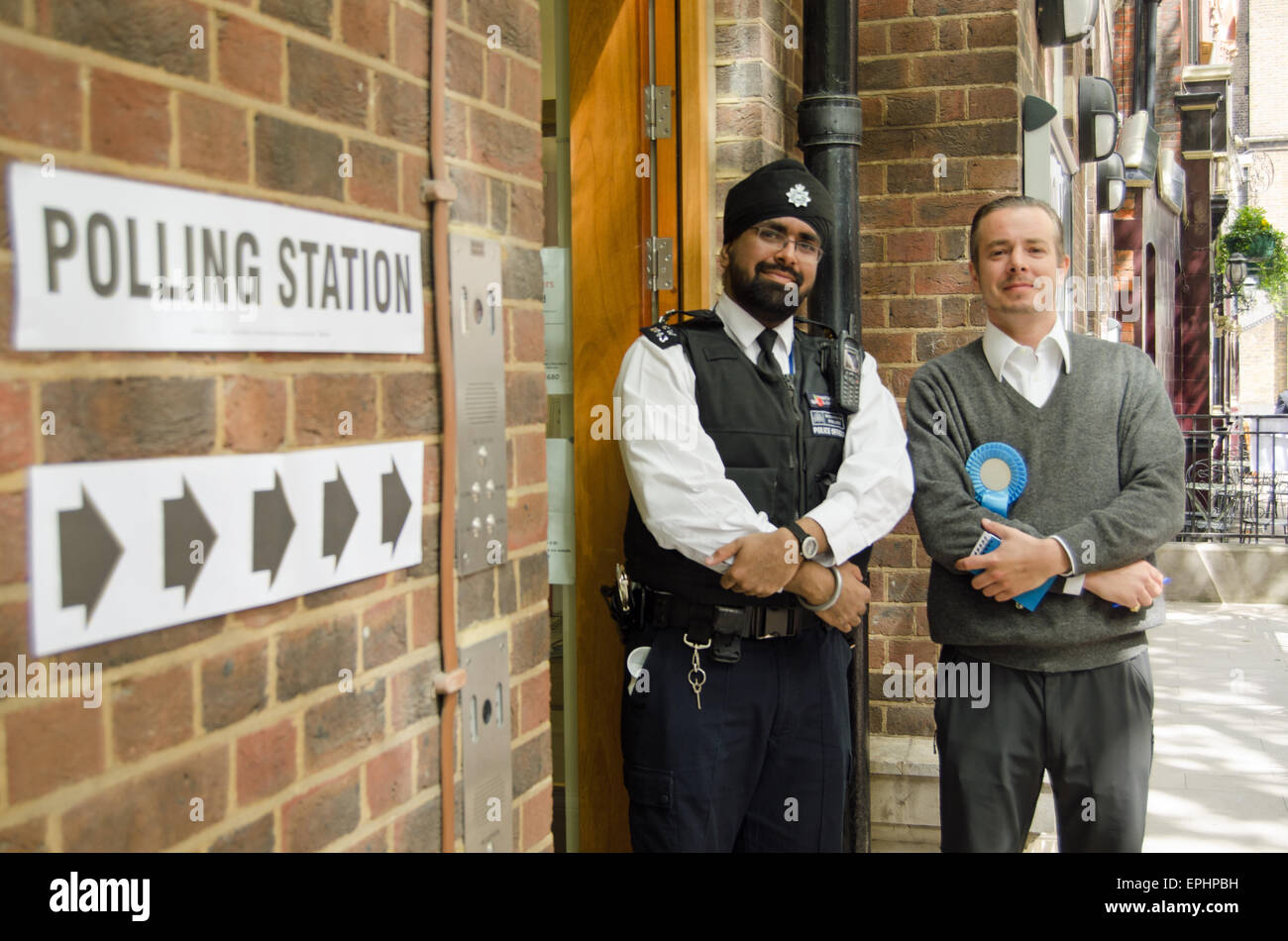 Londra, UK, 7 maggio 2015: un poliziotto e di un Bancomat dal partito conservatore al di fuori della stazione di polling in Westminster London Foto Stock