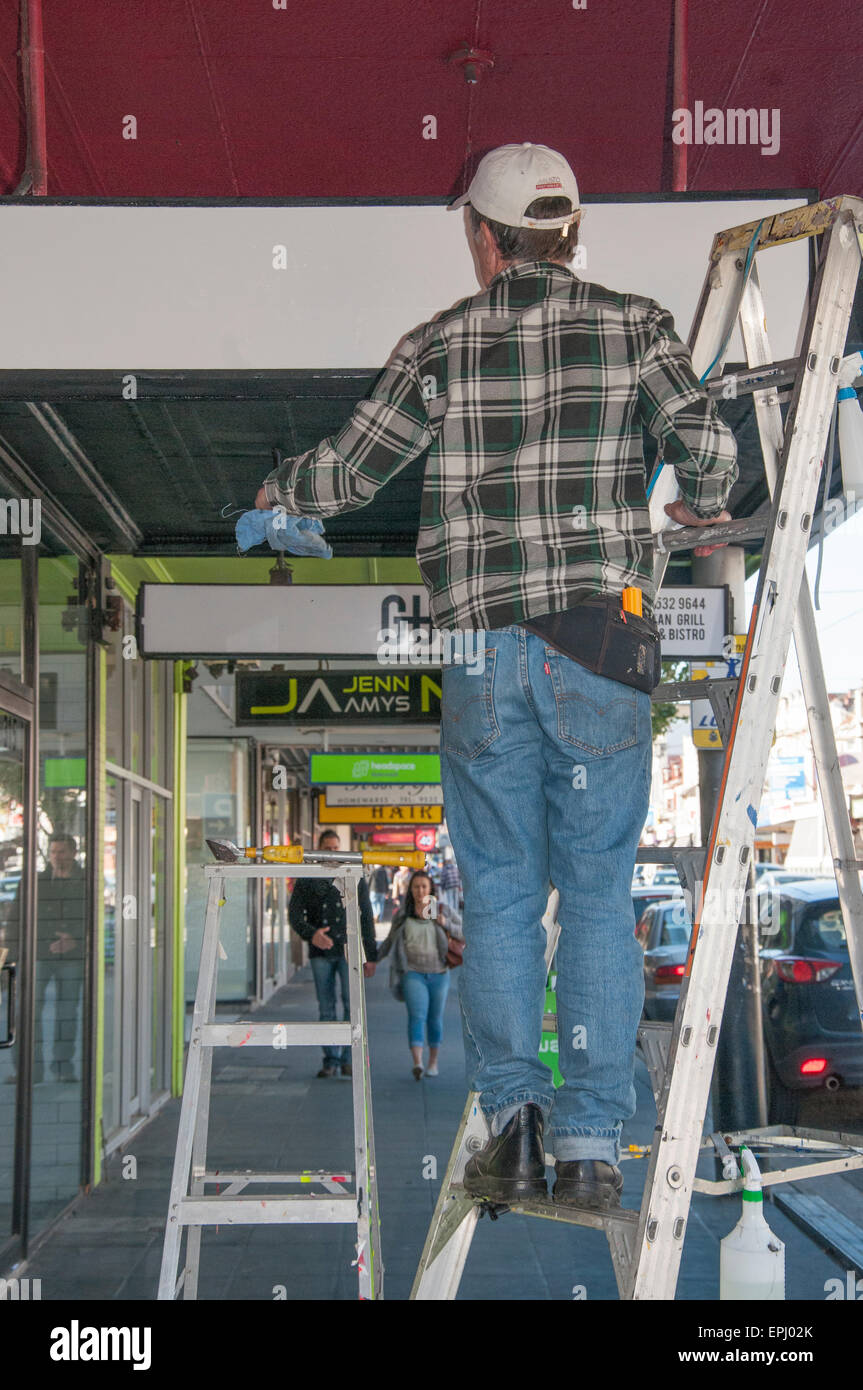 Signwriter al lavoro su un business al dettaglio in Glenhuntly Road, Elsternwick, Melbourne Foto Stock