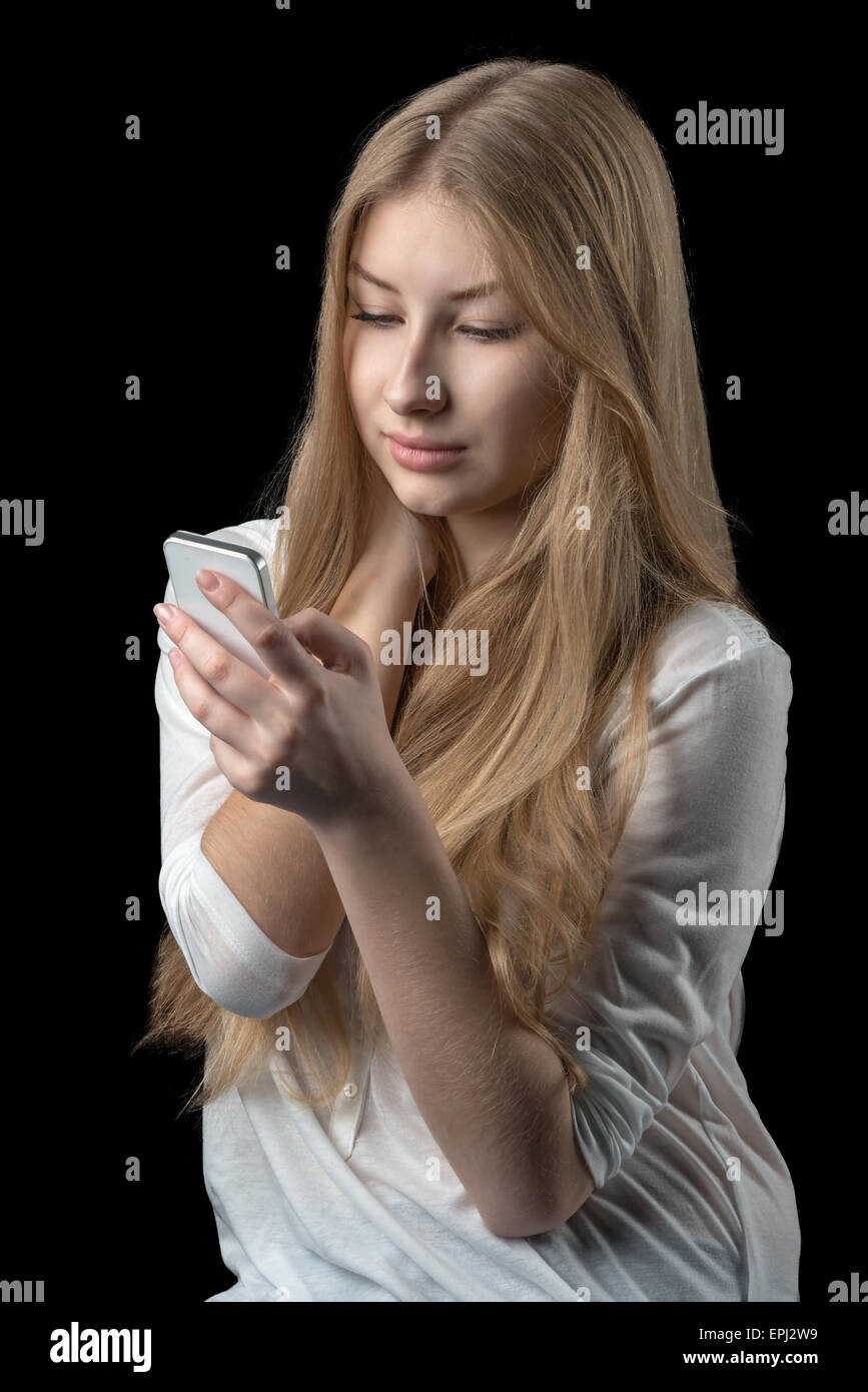 Giovane ragazza piuttosto godendo di chat su internet sulla sua personale di telefonia mobile cellulare. Isolato su nero. Foto Stock