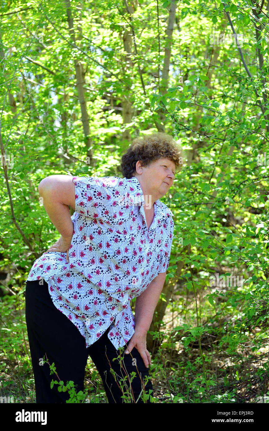 Donna matura con il mal di schiena in una natura Foto Stock