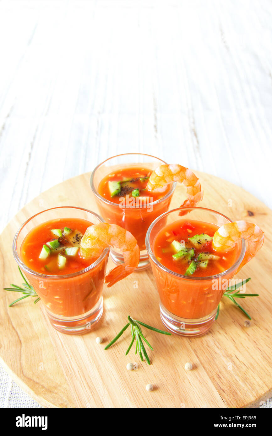 Delizioso freddo gustosa minestra di pomodoro gazpacho con avocado e gamberi nella porzione bicchieri sulla tavola di legno, closeup, verticale Foto Stock