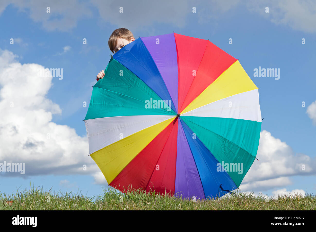 Giovane ragazzo nascosto dietro un ombrello Foto Stock