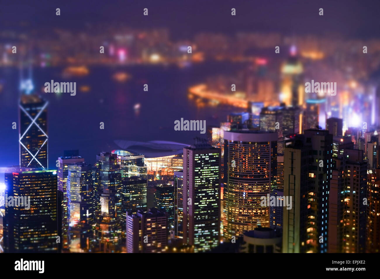 Notte Vista aerea panorama della skyline di Hong Kong e del porto di Victoria. Tilt Shift effetto. Abstract paesaggio urbano futuristico con modernamente Foto Stock