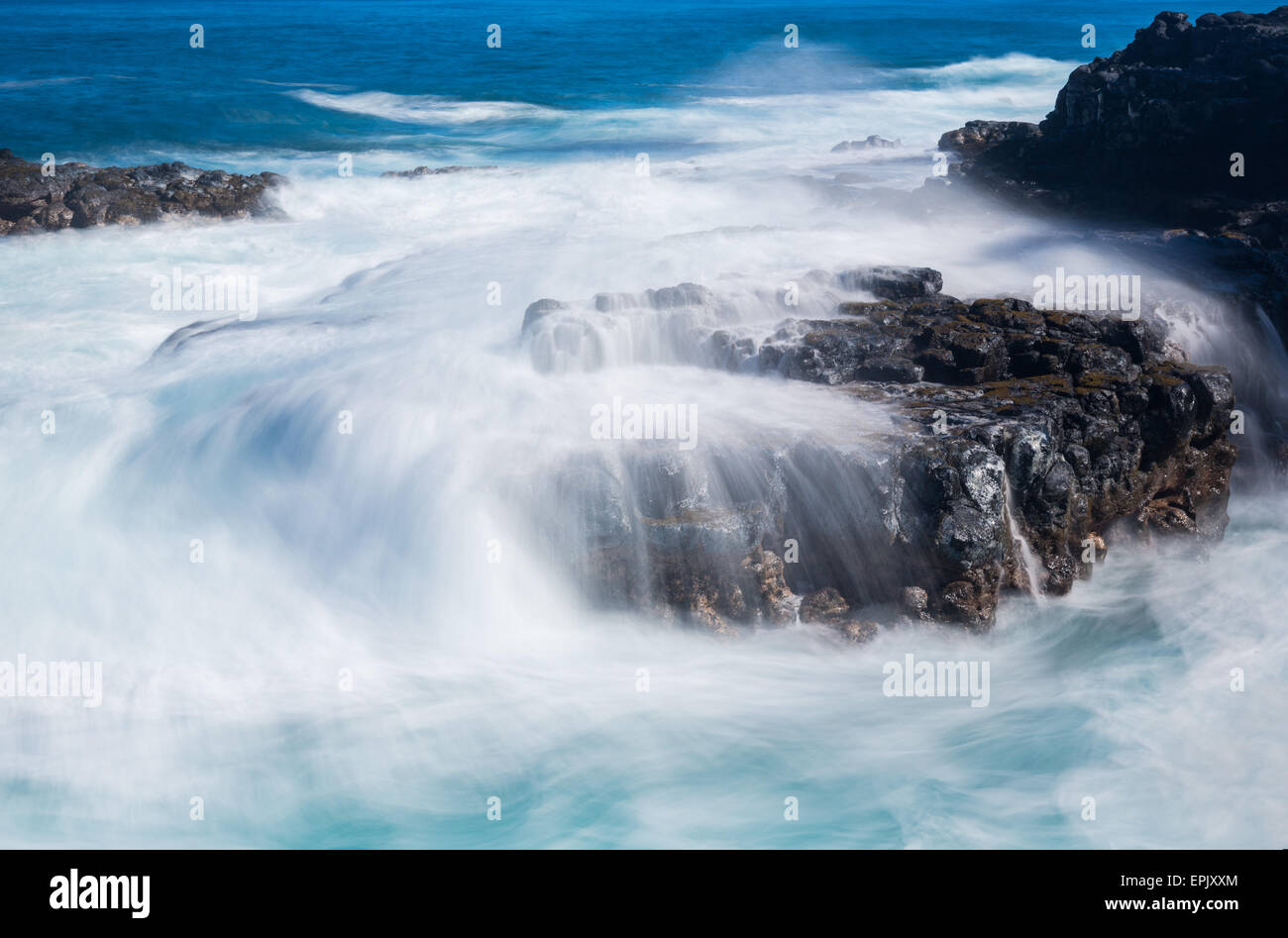 Infuriano mare fluisce sulle lave rocce sulla linea del litorale Foto Stock