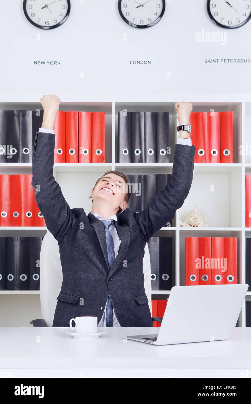 Fiducioso giovane impreditore trionfo guardando al laptop Foto Stock