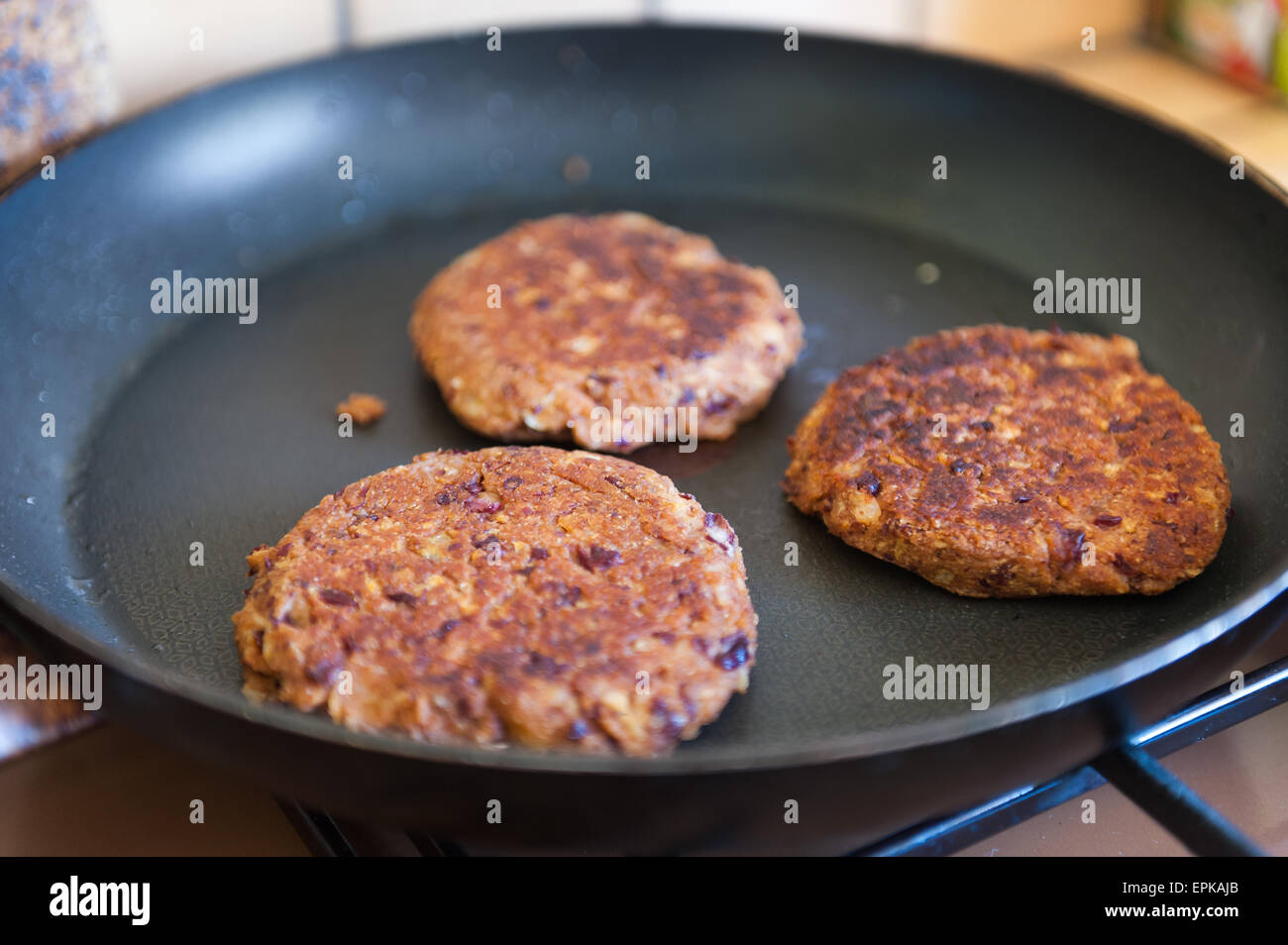 In casa veggie fagiolo hamburger frittura in pochissimo olio in antiaderente Teflon padella Foto Stock