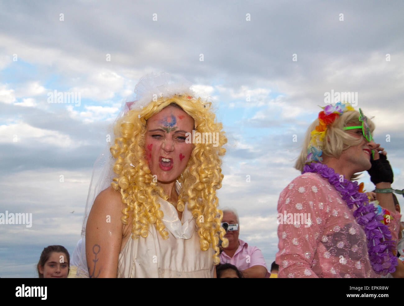 Mad sposa in una parentesi parrucca bionda fare una divertente volto alla telecamera è parte di un polacco street theater Foto Stock