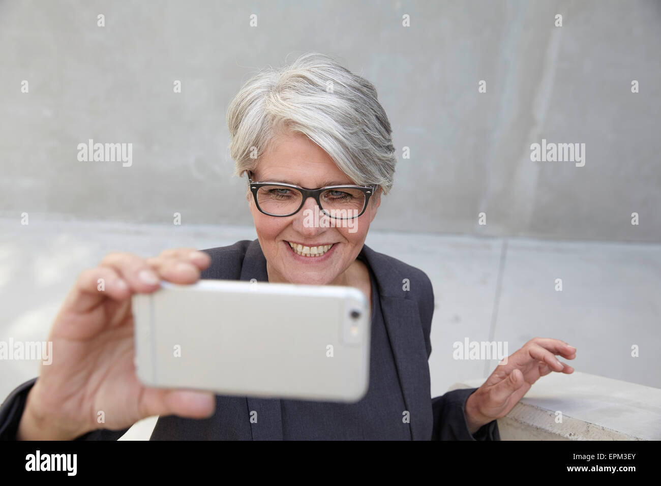 Ritratto di sorridere donna di carriera prendendo un selfie con lo smartphone Foto Stock