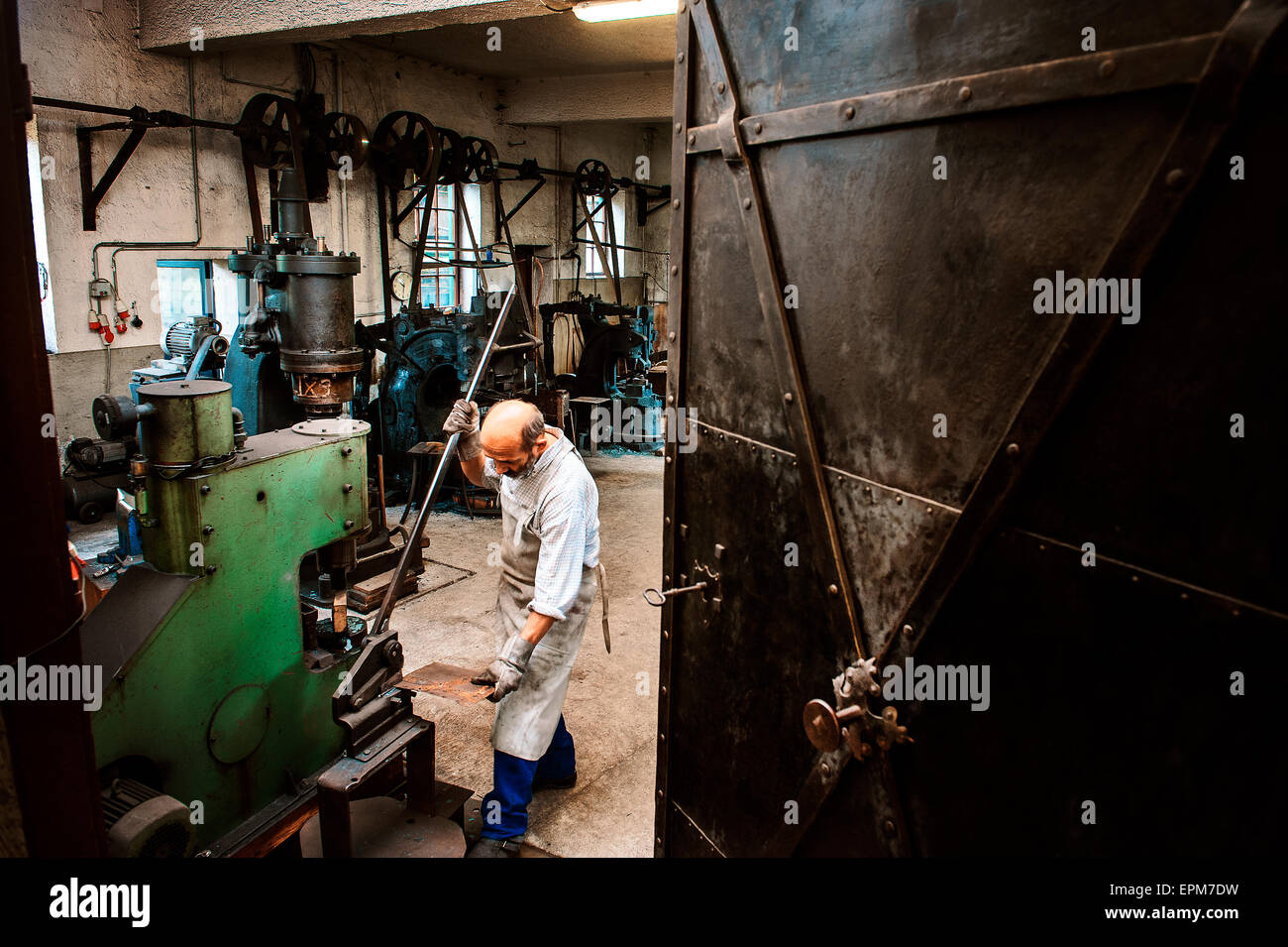 Senior fabbro lavora in un mulino a martelli Foto Stock