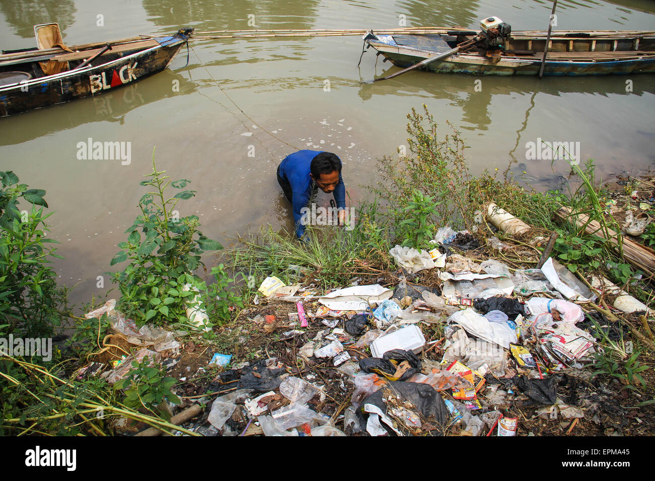 Tangerang, Indonesia. 18 Luglio, 2014. Dodi (38 anni), che lavora come un baco da seta asilo (Tubifex), è alla ricerca di bachi da seta al fiume Cisadane, Tanah Gocap, Tangerang. Dodi giorno può ottenere 25-30 lattine per tin bachi da seta per 5 mila e venduti in negozi di pesce in Tangerang. © Garry Andrew Lotulung/Pacific Press/Alamy Live News Foto Stock