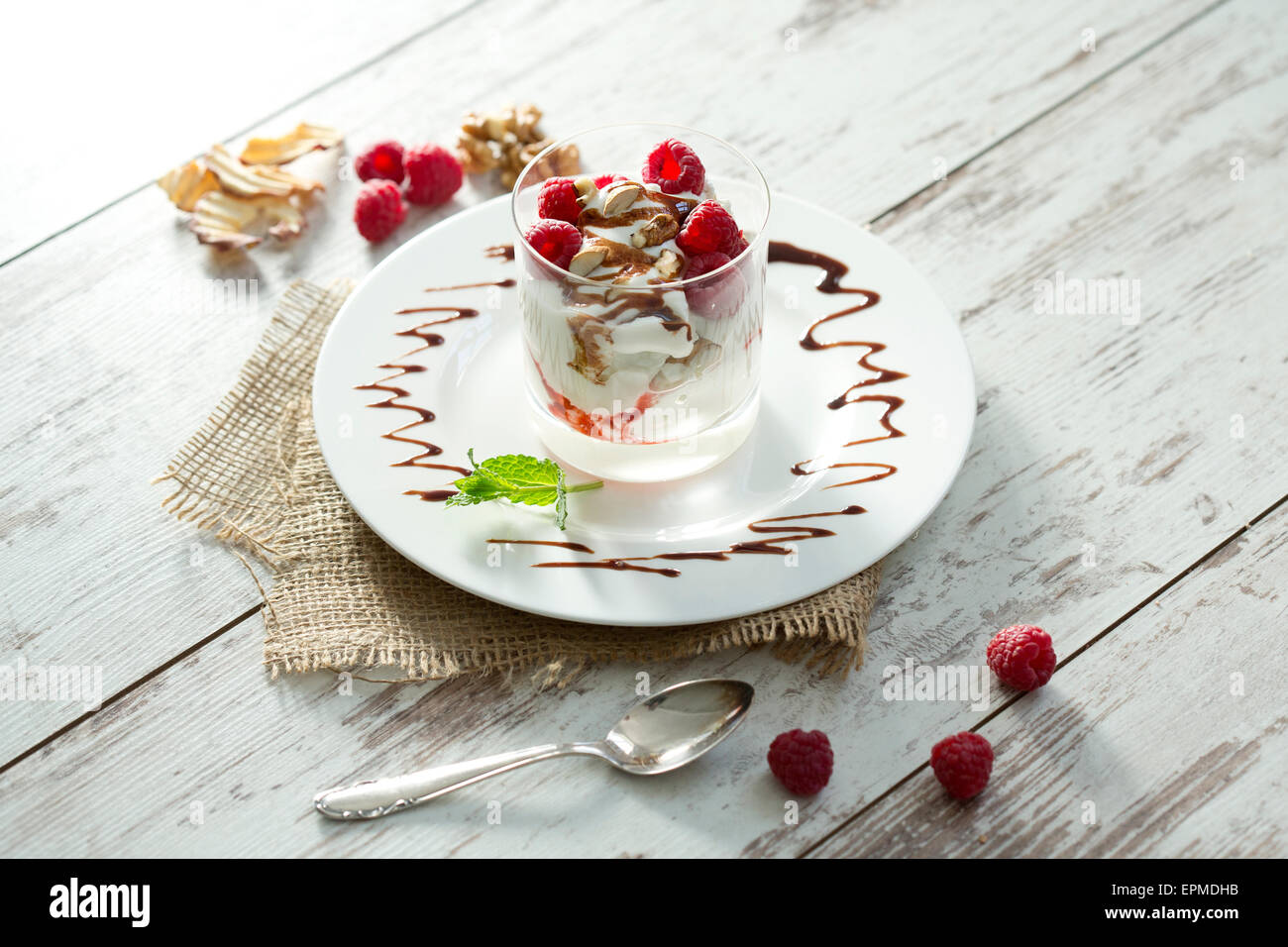 Il dessert in vetro con lamponi, latticini, yogurt essiccata apple, bastoncini di mandorle e salsa al cioccolato Foto Stock
