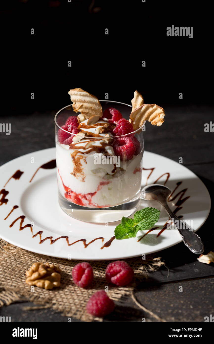 Il dessert in vetro con lamponi, latticini, yogurt essiccata apple, bastoncini di mandorle e salsa al cioccolato Foto Stock