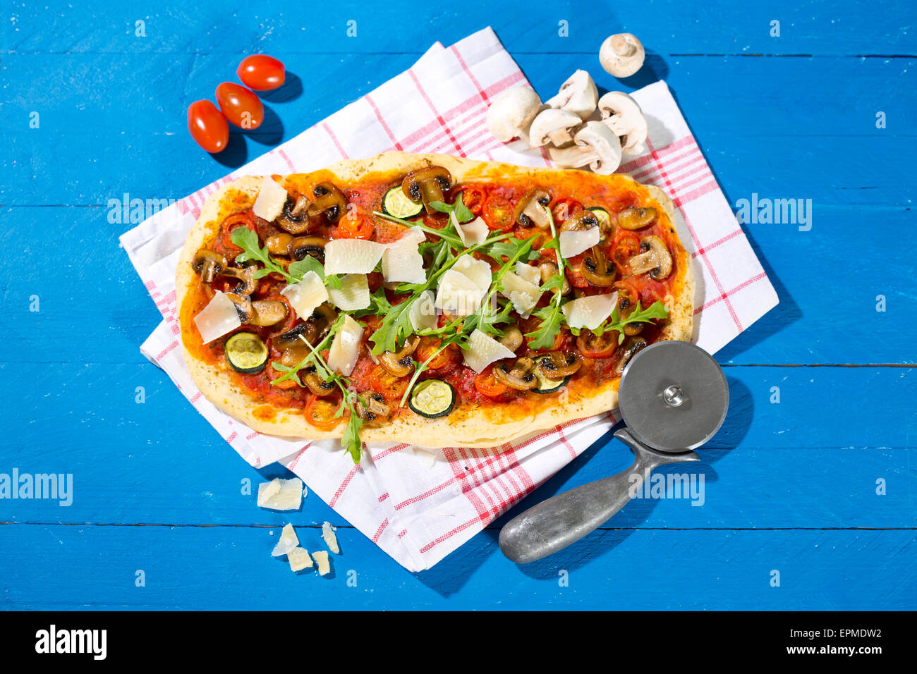 La pizza fatta in casa con gli champignon, rucola, zucchine, pomodori e parmigiano Foto Stock