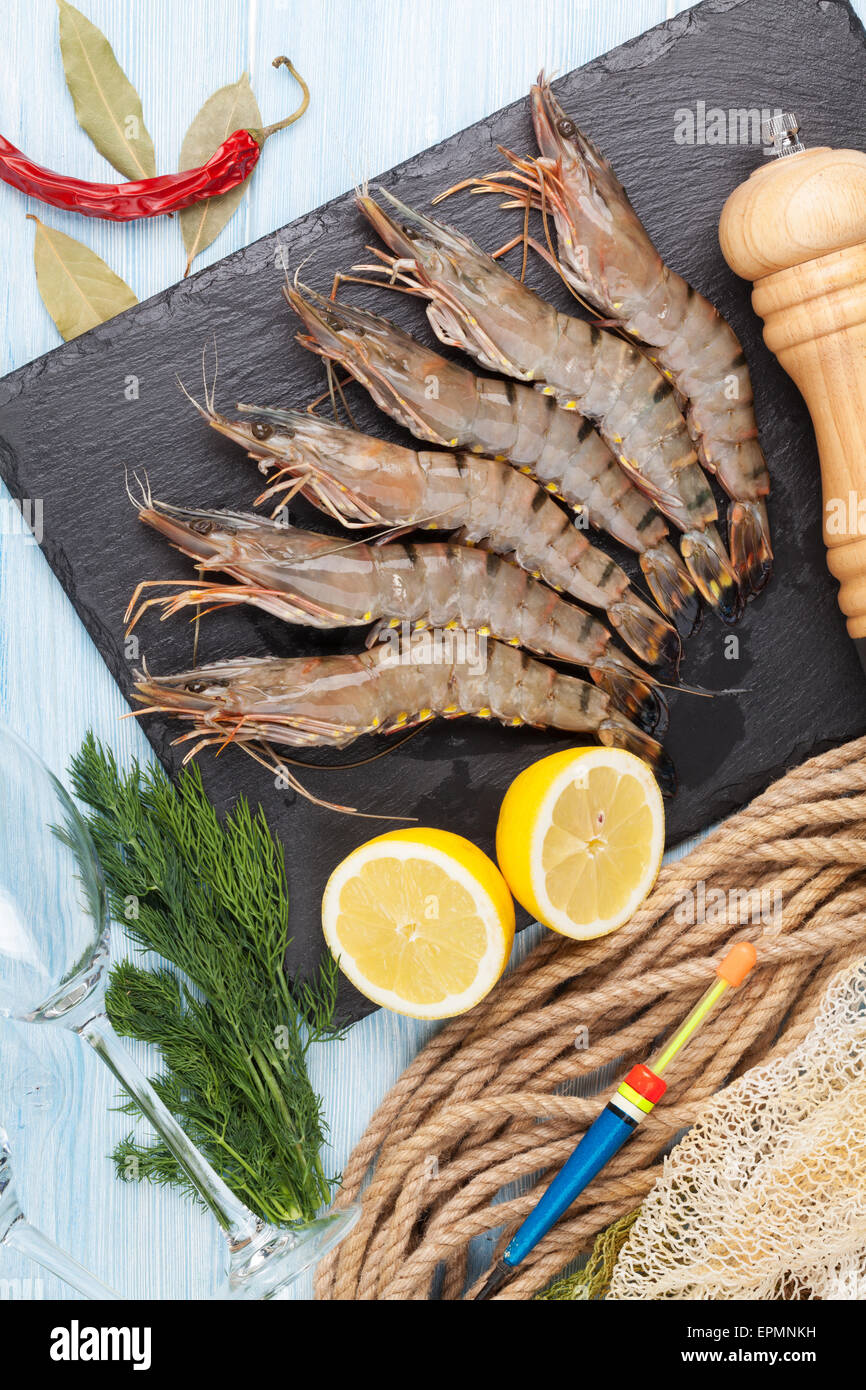 Crudo fresco gamberoni e attrezzature per la pesca su un tavolo di legno. Vista superiore Foto Stock
