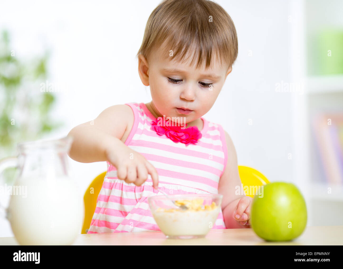 Carino bambina mangia il cibo sano seduta a tavola in vivaio Foto Stock