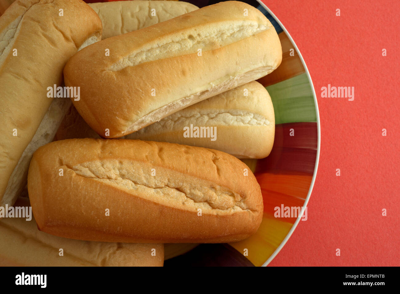 Vista ravvicinata di più appena sfornato il bratwurst i panini su una piastra colorati su un arancio tavolo. Foto Stock