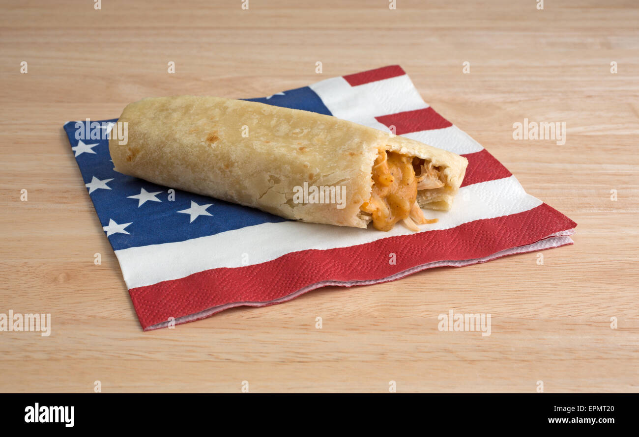 Un formaggio e pollo chimichanga che è stato picchiato su un flag motif igienico in cima a una tavola di legno alto. Foto Stock