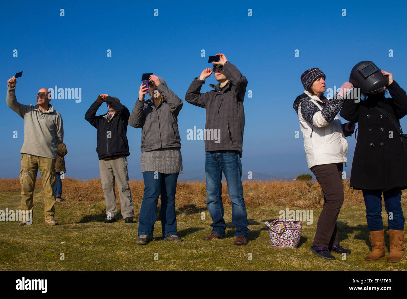 Persone che guardano la specacular parziale eclissi solare, XX marzo, 2015, sulla brughiera, Penisola di Gower, Wales, Regno Unito Foto Stock