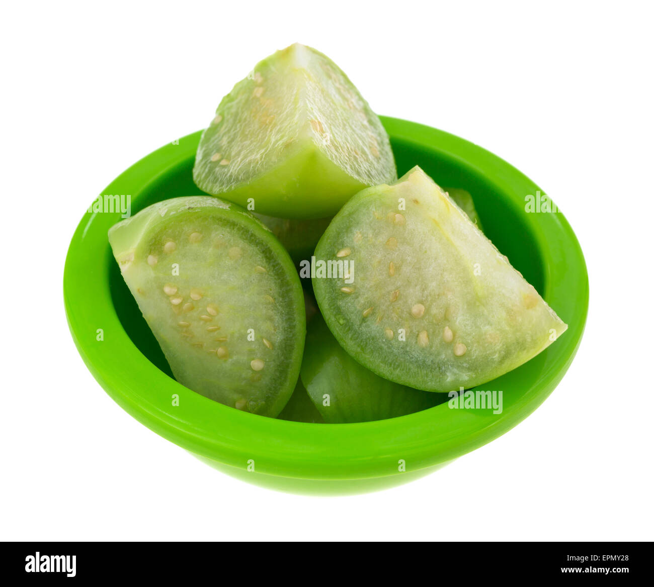 Diverse sezioni di taglio tomatillos in un piccolo piatto verde isolato su uno sfondo bianco. Foto Stock