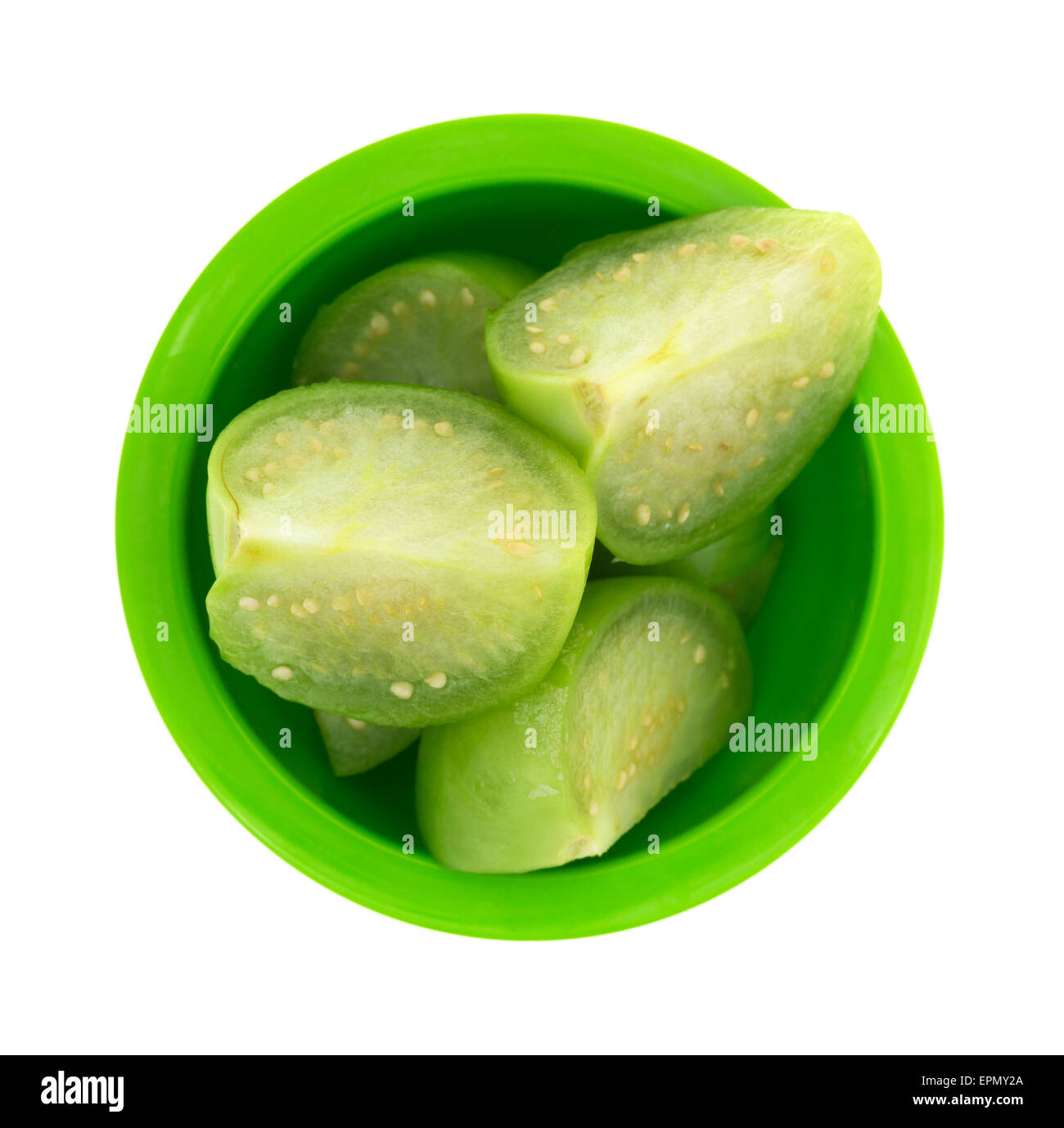 Vista dall'alto di diverse sezioni di taglio tomatillos in un piccolo piatto verde isolato su uno sfondo bianco. Foto Stock