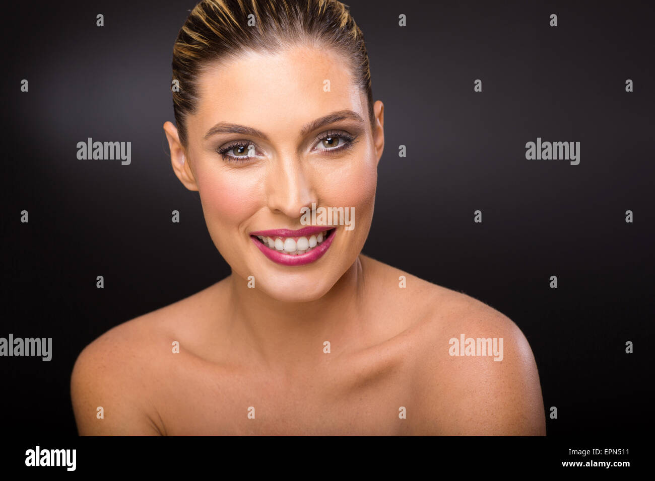 Felice donna bionda con trucco pulito su sfondo nero Foto Stock