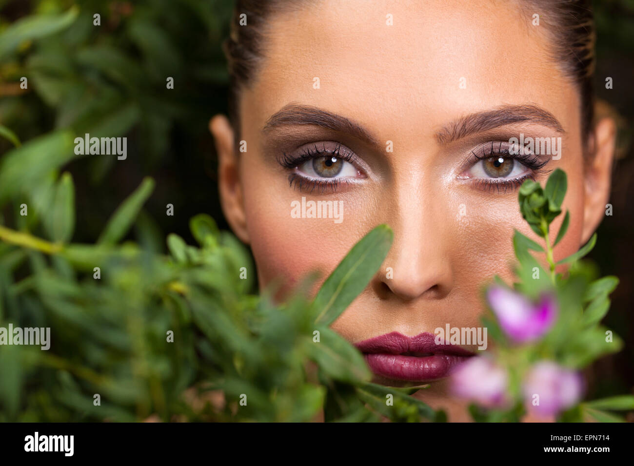 Bella giovane donna in posa tra il verde delle foglie Foto Stock