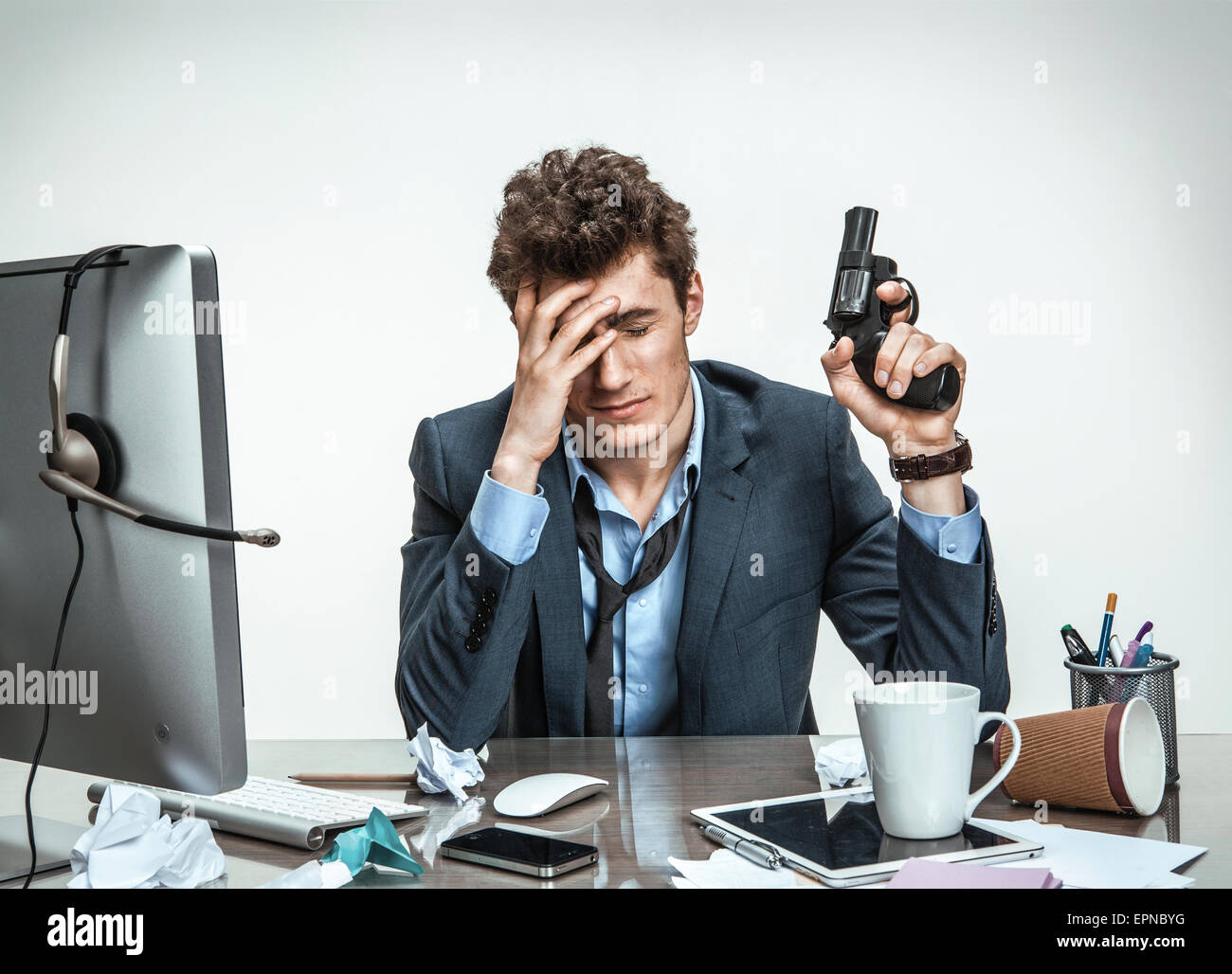 Giovane imprenditore con la pistola vuole suicidarsi / ufficio moderno uomo al posto di lavoro, depressione e il concetto di crisi Foto Stock