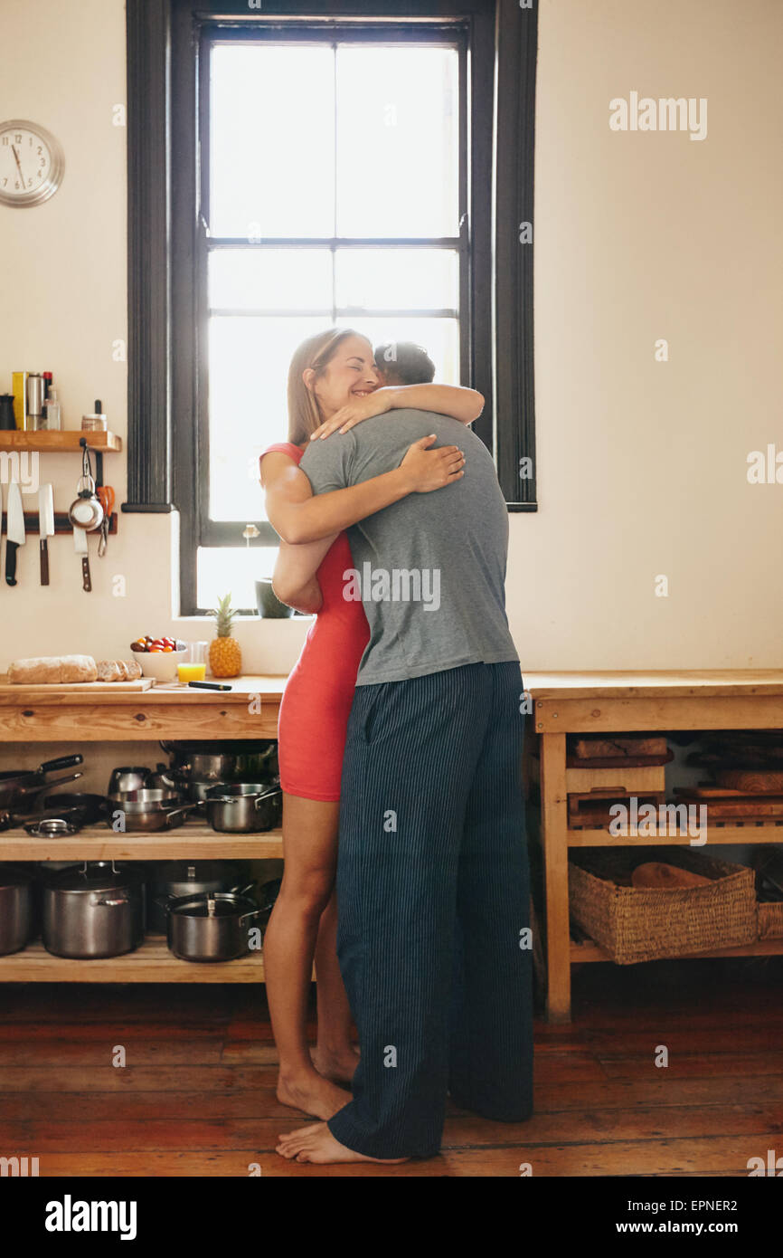 Piscina colpo di coppia giovane che abbraccia ogni altra in cucina. Lunghezza completa immagine di uomo abbracciando la donna in mattina. Augurando buona giornata Foto Stock