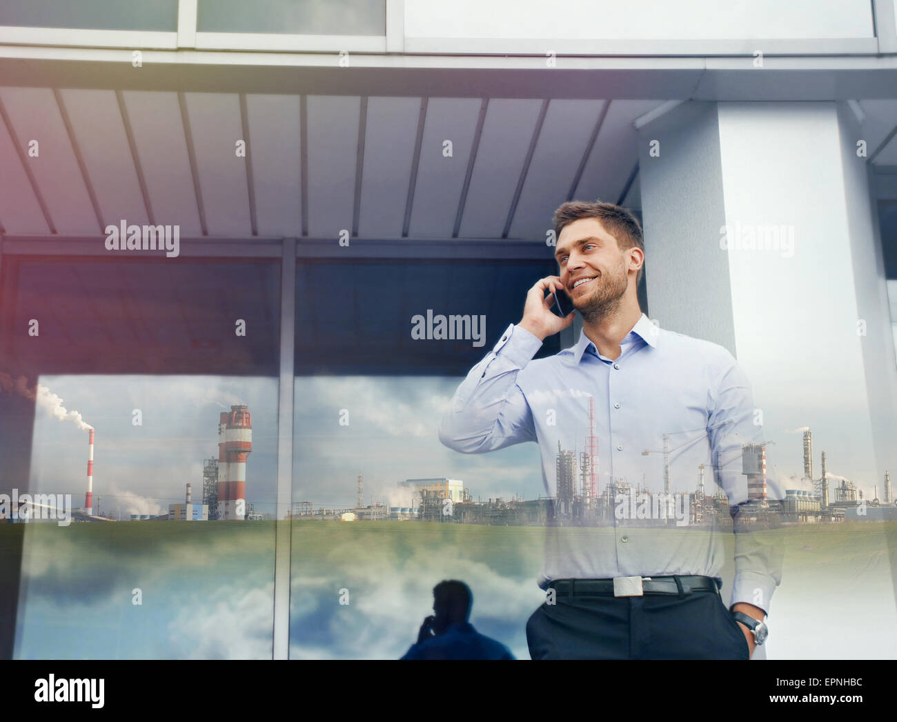Doppia esposizione di imprenditore con dispositivo telefonico e impresa industriale su edificio urbano sfondo Foto Stock