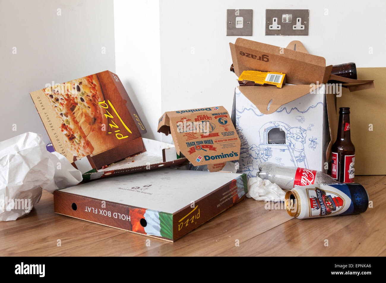 Il fast food figliata. Scartato lattine, bottiglie e da asporto scatole per pizza sul pavimento in corrispondenza di un bordo di una camera, REGNO UNITO Foto Stock