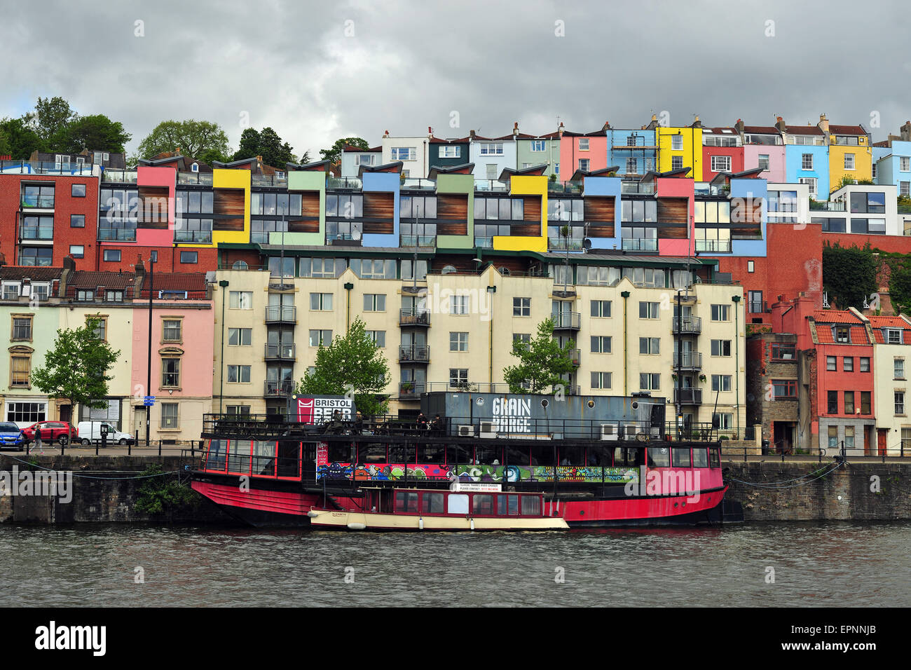 Barche ormeggiate sul lato del porto di Bristol con case colorate in background. Foto Stock
