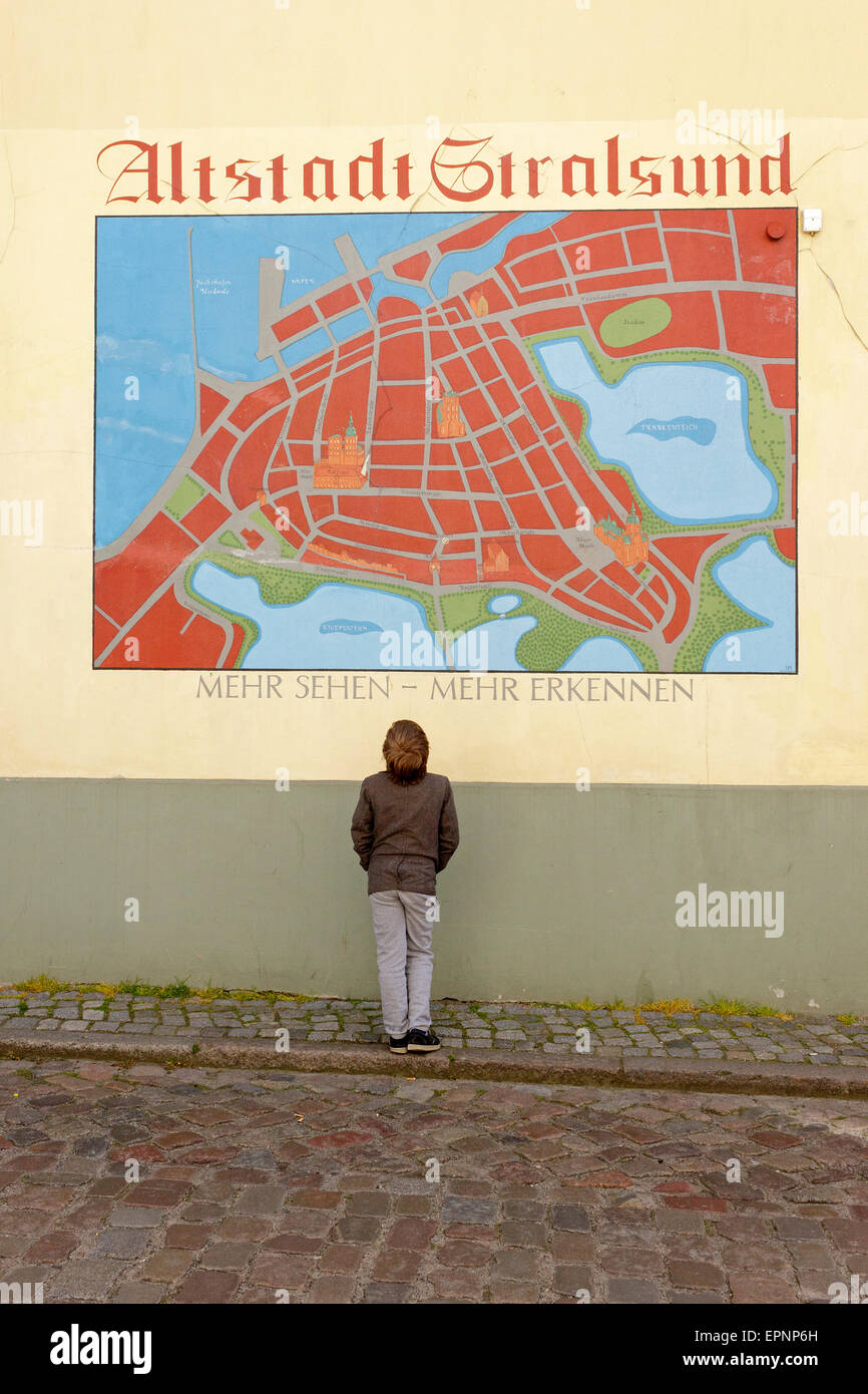 Ragazzo che guarda alla mappa città dipinta su un muro, Stralsund, Meclemburgo-Pomerania Occidentale, Germania Foto Stock