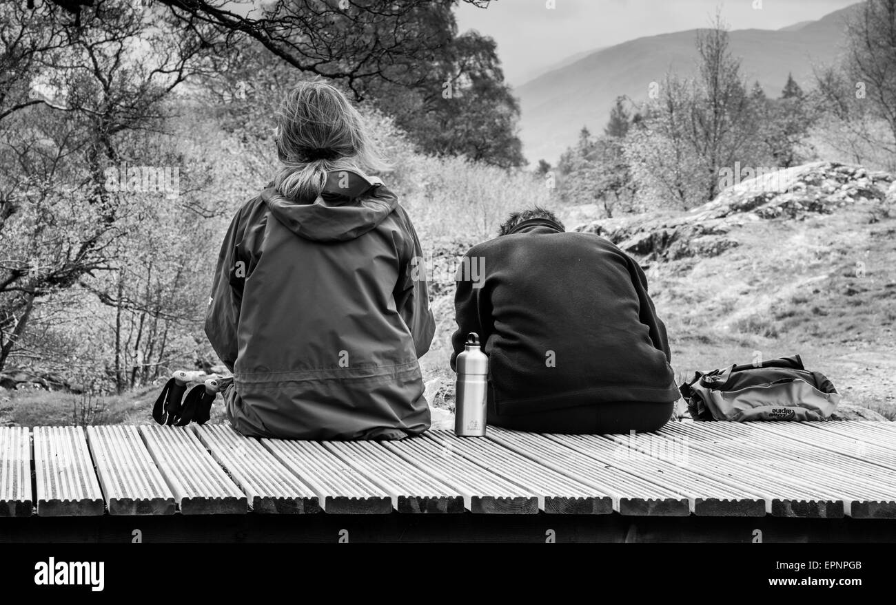 Due escursionisti picnic sul ponte che attraversa la parte superiore scende di Aira Beck, al di sopra di Aria forza, vicino a Ullswater, Lake District, Cumbria Foto Stock