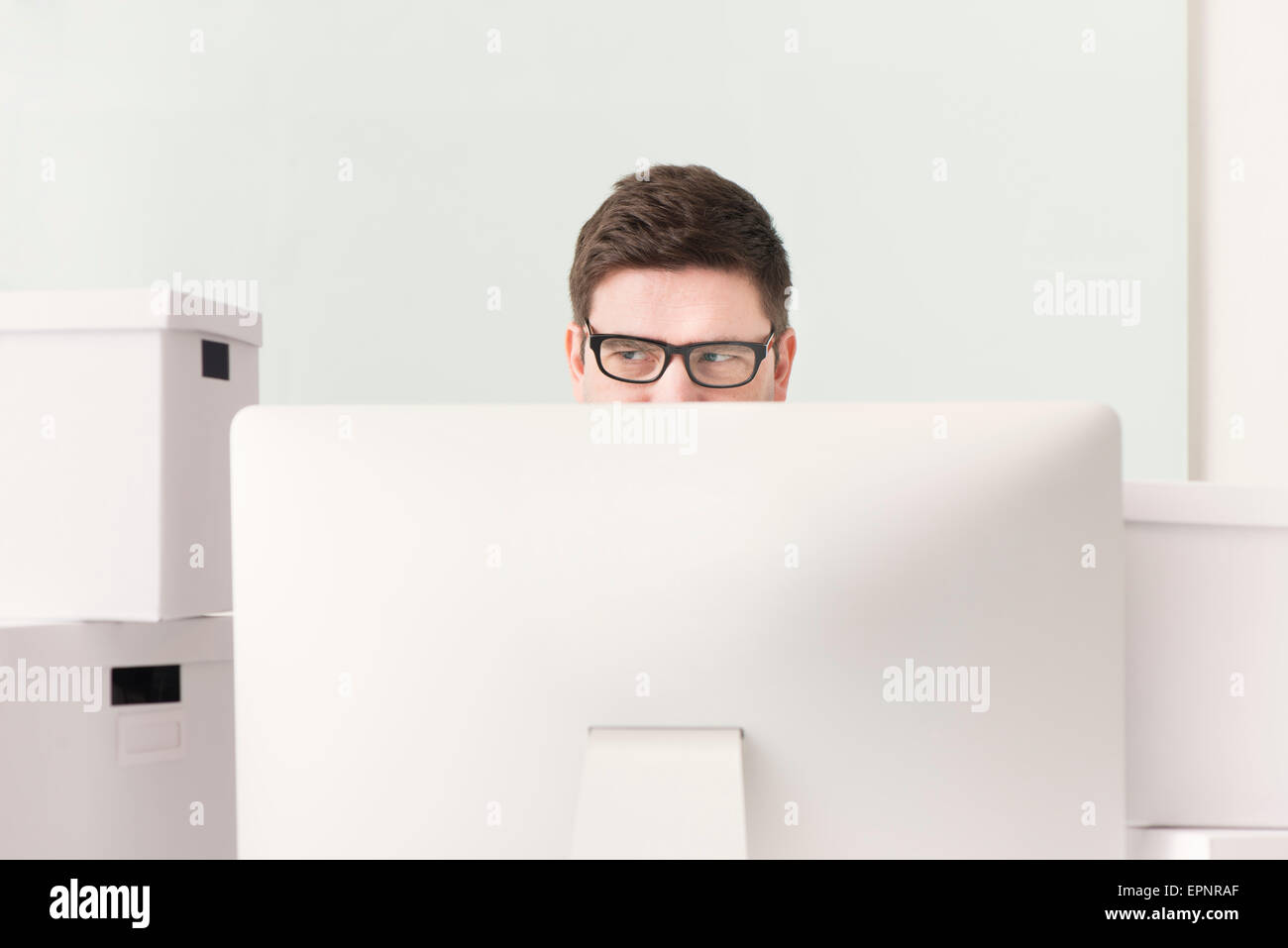 Imprenditore lavora con il computer alla scrivania. Egli è circondato da caselle bianche utilizzati per la movimentazione. Immagine concettuale del business Foto Stock